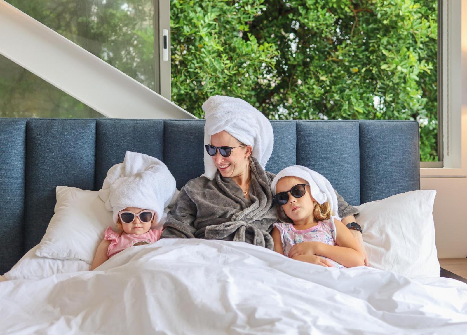 Mom and two daughters in bed with sunglasses at Lobster Villa by Nox Rentals